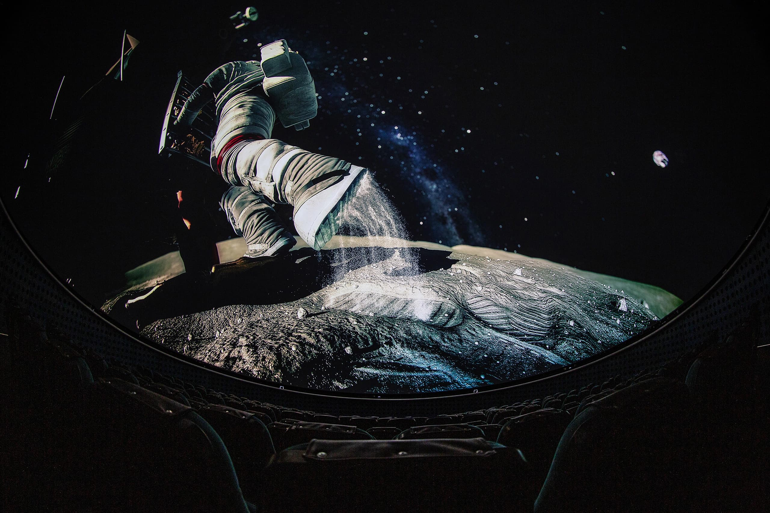 Astronaut and lunar surface projected across a planetarium dome